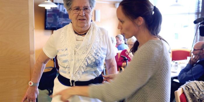 Skjoldvor Måsøval, resident at the Laugsand day care centre, is helped by a scientist to adjust the belt that will trigger an alarm if she is unlucky and falls. Photo: Kjersti Fikse Ness, Adresseavisen