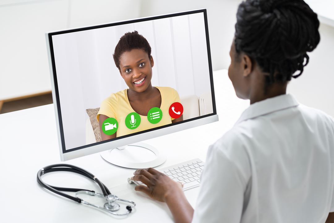 En kvinnelig lege ser på en dataskjerm med en kvinnelig pasient.