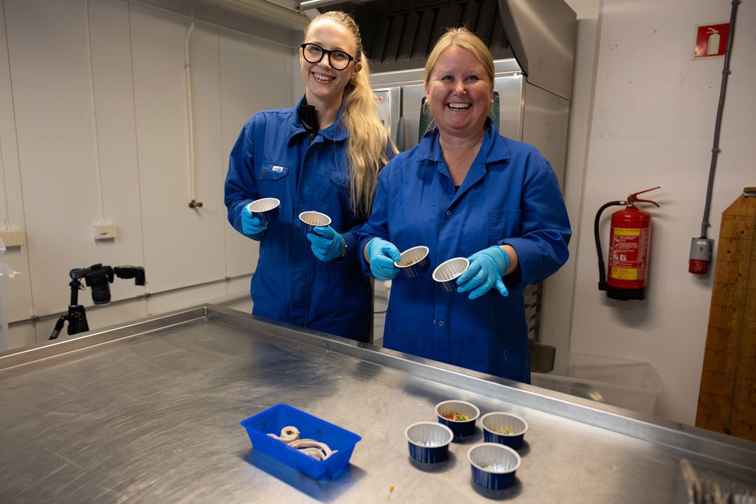 To forskere i blå frakker med slimålfileter.