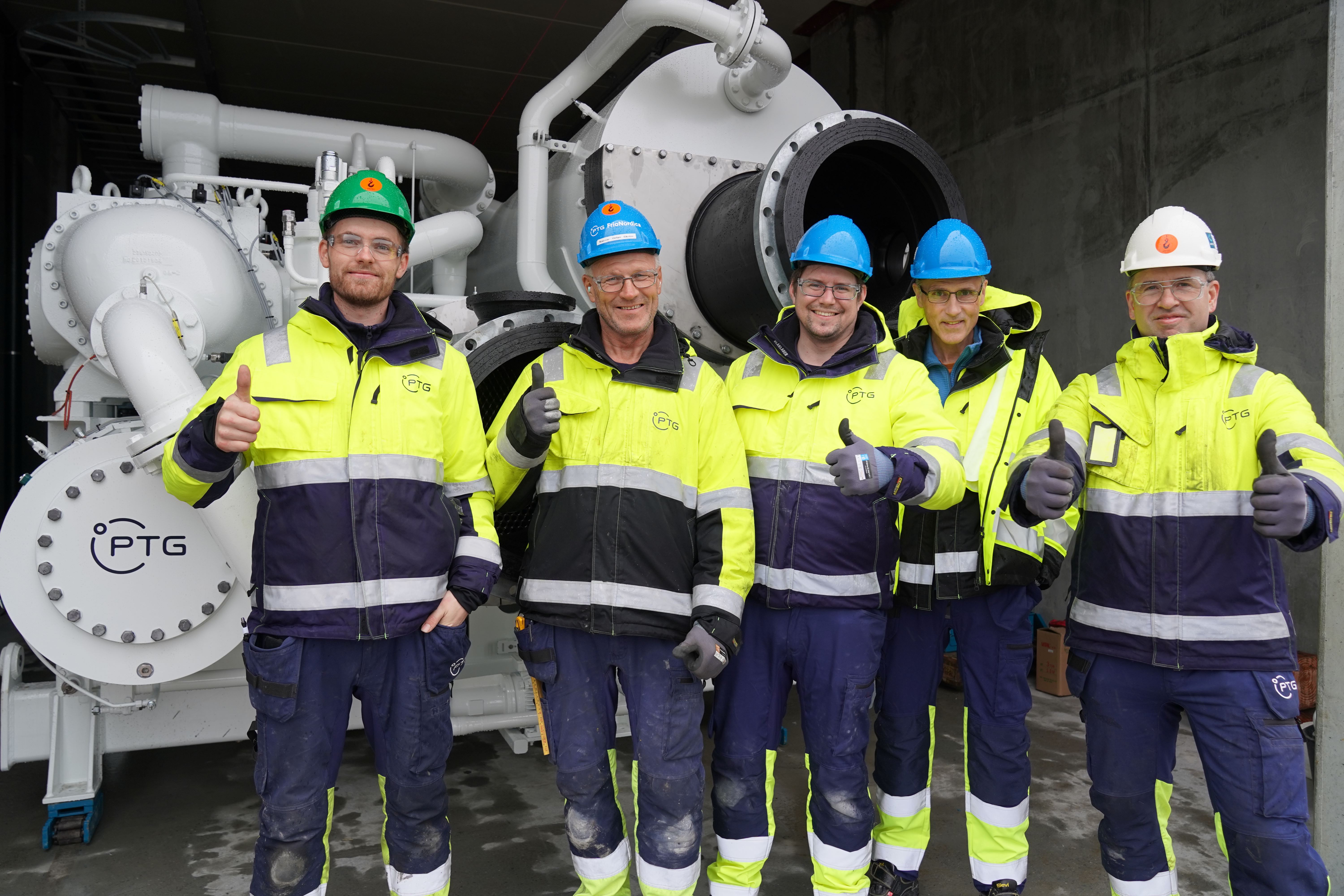 PTG employees standing in front of a gigantic heat pump at Salmon Evolution in Harøy, Romsdal