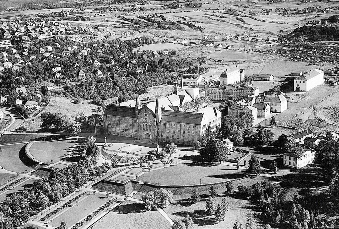 Høgskoleområdet på Gløshaugen, slik det var i SINTEFs første år. Bildet er tatt i september 1952. SINTEFs ledelse hadde kontorer i Kjelhuset, som ruver med sin skorstein midt på bildet. Foto: William Skappel/Widerøe