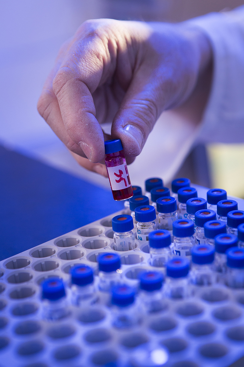 Hånd som tar opp et lite prøveglass