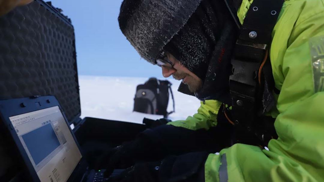 Vegard Hornnes (NTNU) bruker PCen ute i 21 minusgrader. Maskinen er koblet til en borehole jack. Dette er et apparat man setter inn i et borehull for å måle isens mekaniske styrke.