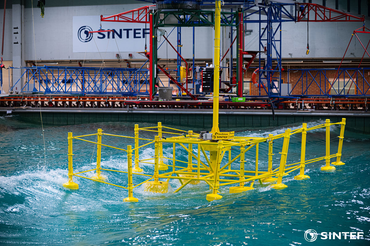 Yellow model of a wave, wind and solar energy platform in the ocean basin.