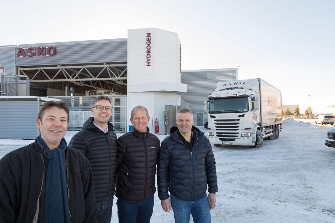 Fire menn, med hydrogenpumpe og lastebil i bakgrunnen