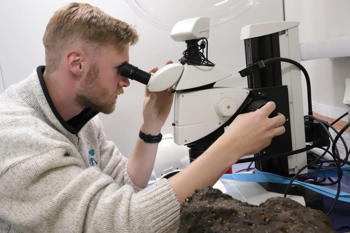 Eirik Siira (UiB) ser på en del av nattens prøvefangst med mikroskop.