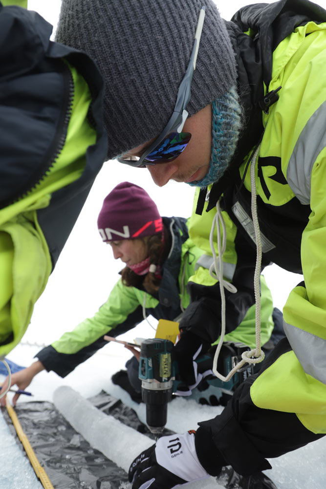 Teamet borer et lite hull i en iskjerne de har nettopp tatt ut av isen for å måle kjernens temperatur. På bildet: Alexandra Pliss og Oskar Gjesdal Veggeland (begge fra NTNU).