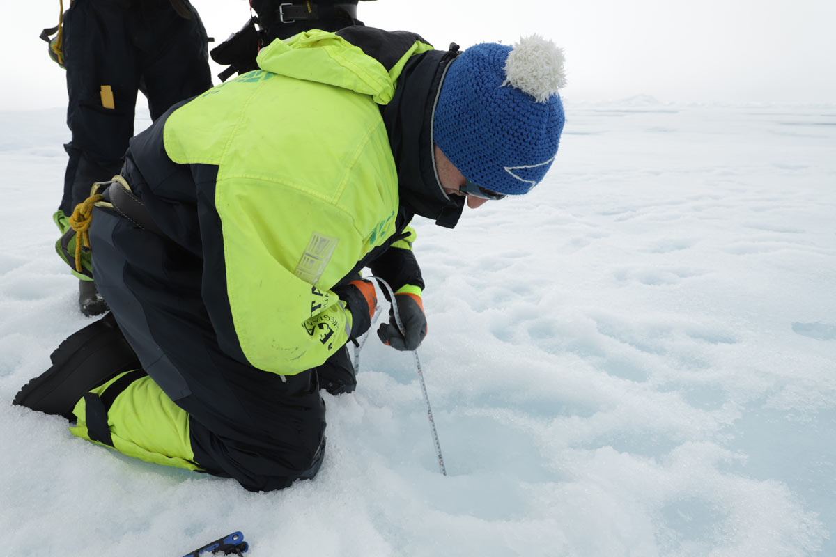 Christian Katlein (AWI) måler et isflaks tykkelse ved et borehull.