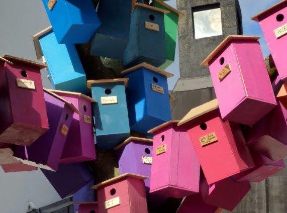 Bildet viser fuglekasser i mange farger.