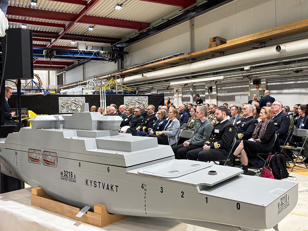 Model of NoCGS Jan Mayen with audience behind.