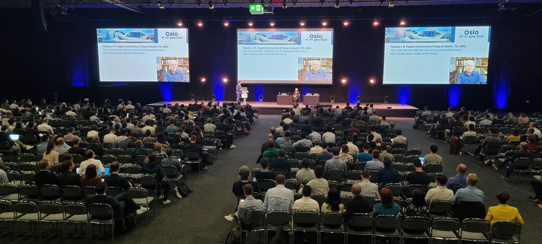 Stor sal full av mennesker og to menn på scenen