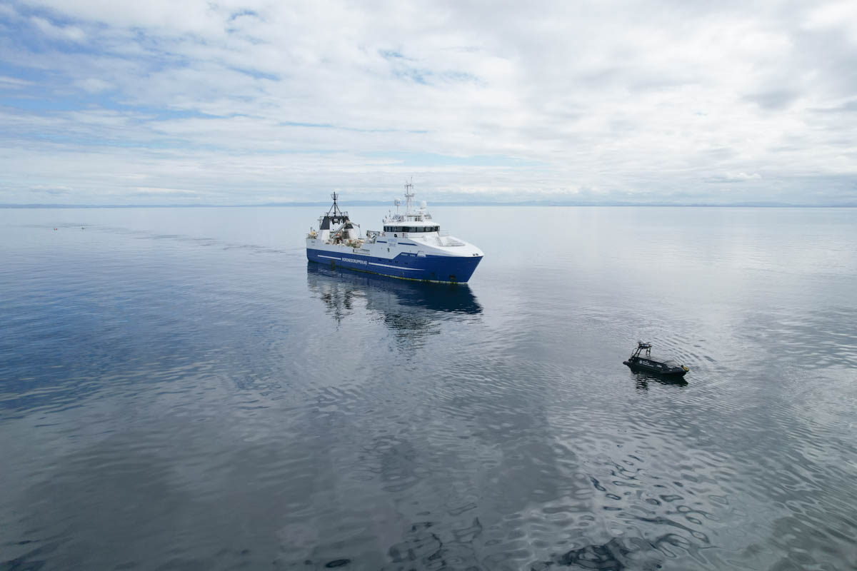 Fishing trawler with USV in front in calm waters.