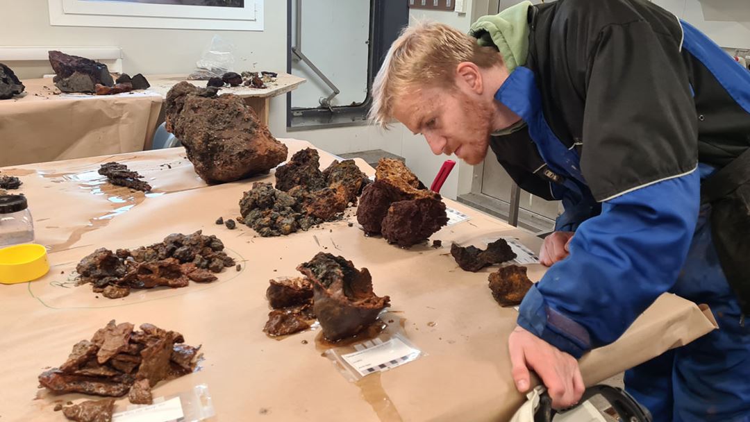 Eirik Valdar (UiT/UiB) ser på dagens fangst av steinprøver. Den skålformede steinen han ser på er dekket på innsiden av slimete organisk materiale.
