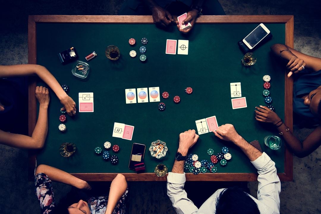 Fem personer sitter rundt et bord og spiller poker