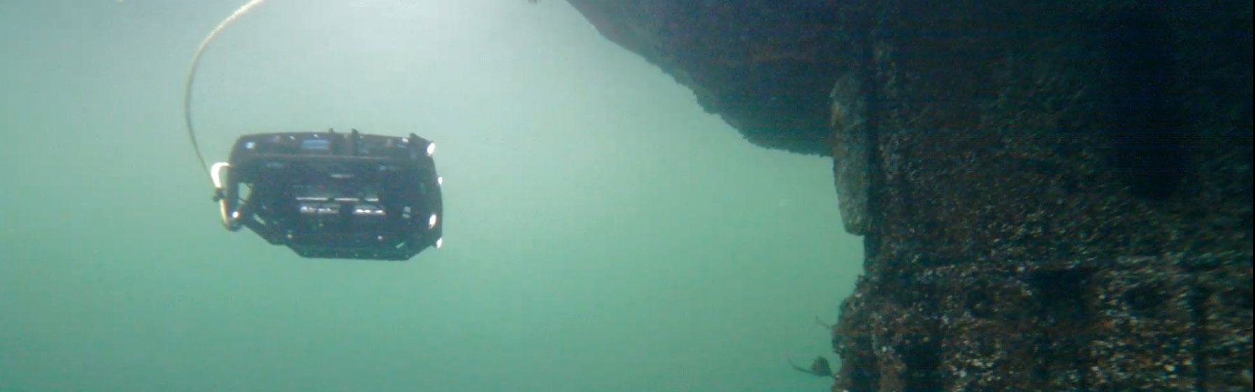 Underwater robot in green murky water.