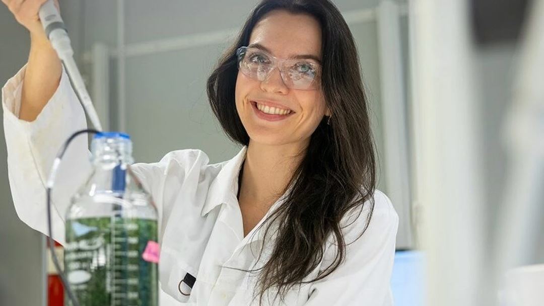 Kvinnelig forsker som pippeterer fra en flaske med grønt innhold.