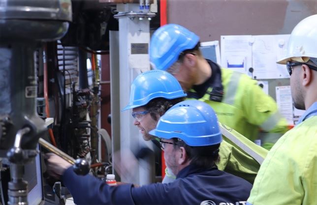 Four persons with helmets working on a machine