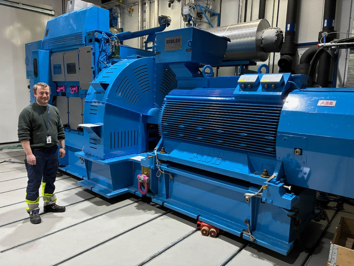 Researcher standing next to a large, blue engine.