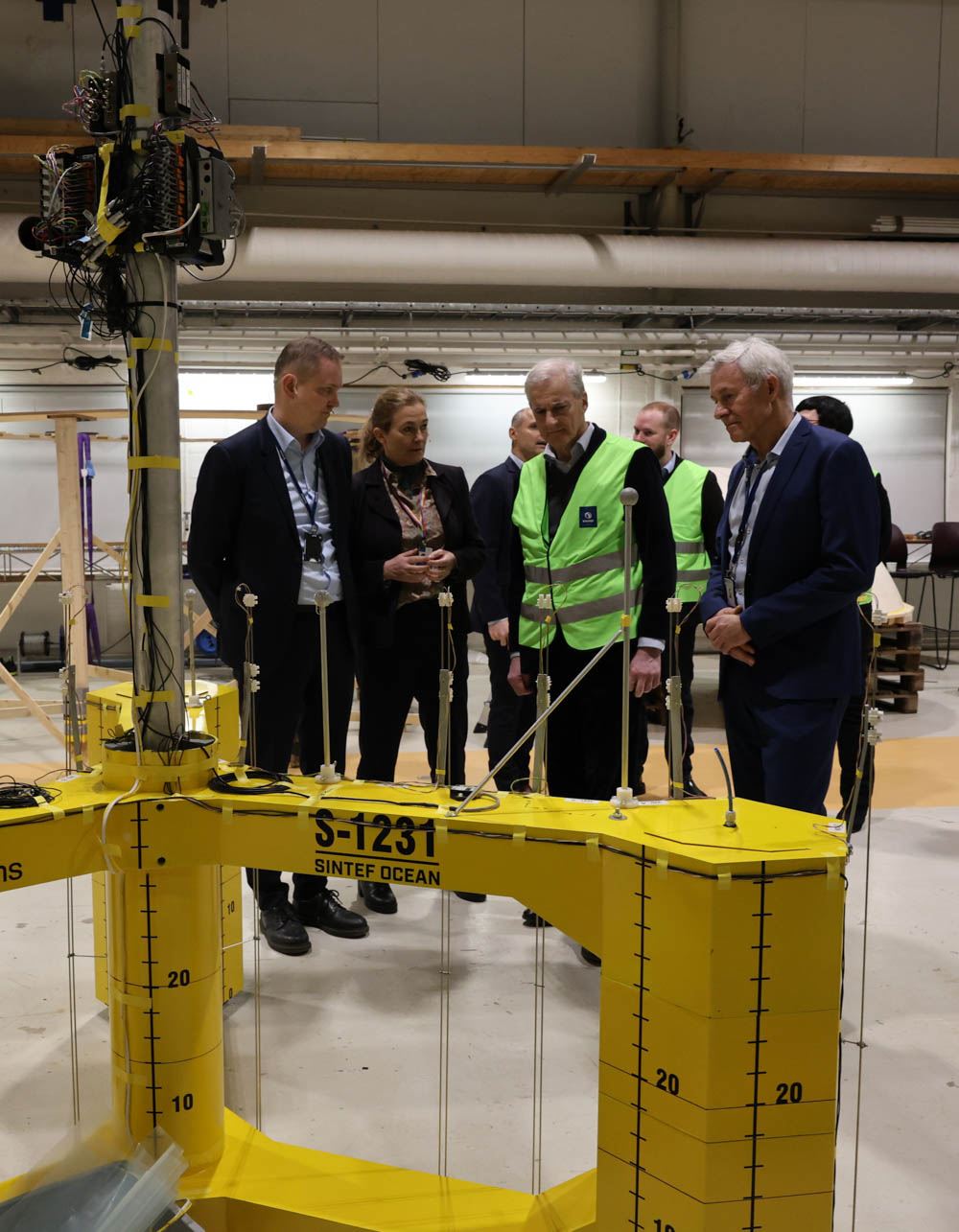 Flytende vindturbinmodell med fire mennesker som ser på bak.