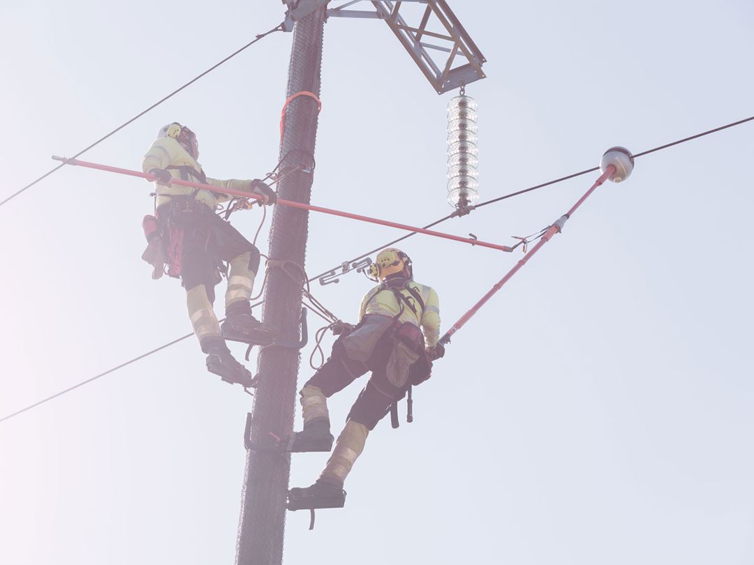 To menn har klatrer opp i strømmast og monterer sensor i strømledning