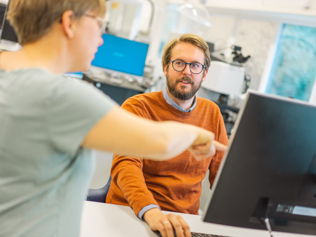 Forsker og kunde diskuterer innovatove problemstillinger rundt en pc-skjerm