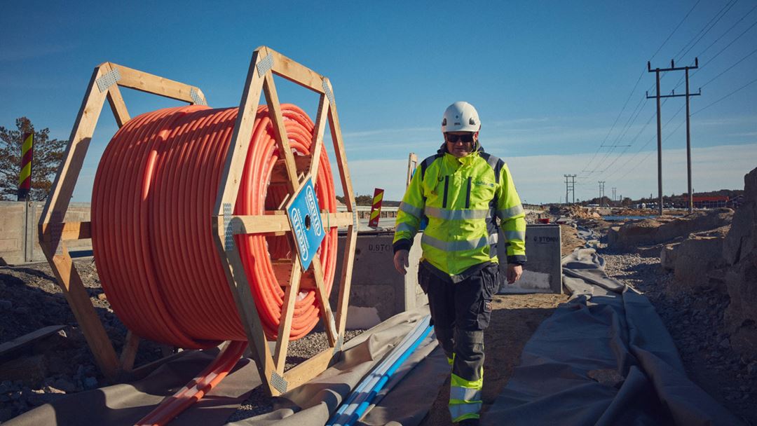 trommel med ledninger og en mann i gule arbeidsklær