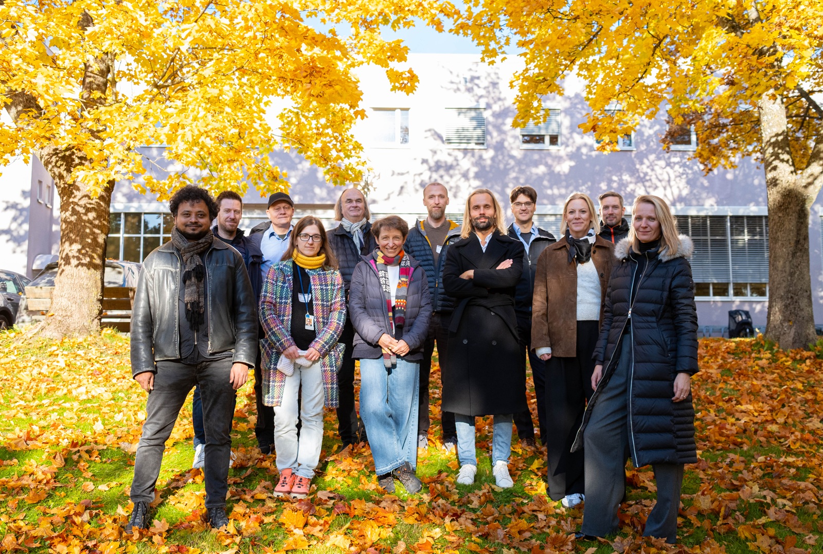 Partnere i prosjektet: 12 personer står under et høstfarget tre