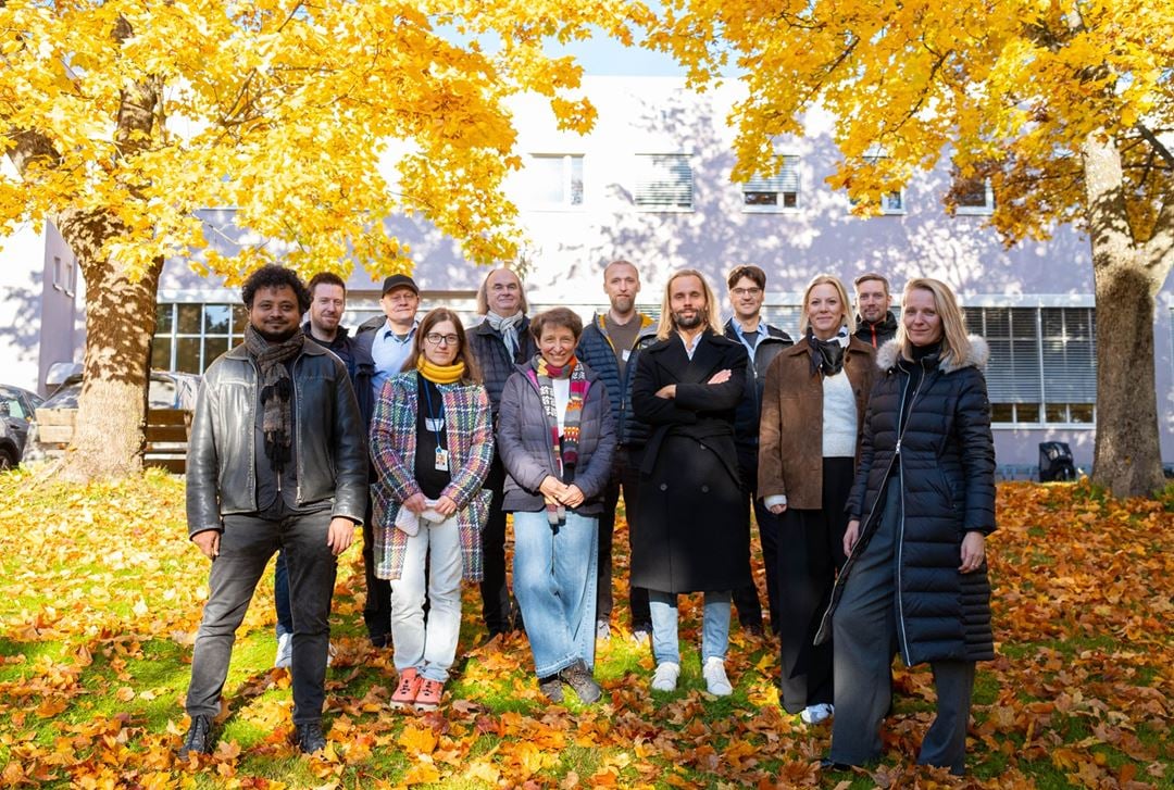 Partnere i prosjektet: 12 personer står under et høstfarget tre