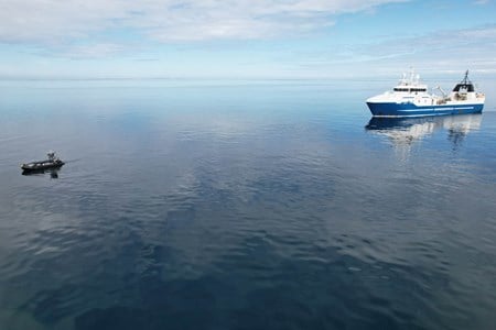 Fiskebåt på blikkstille vann med USV foran.