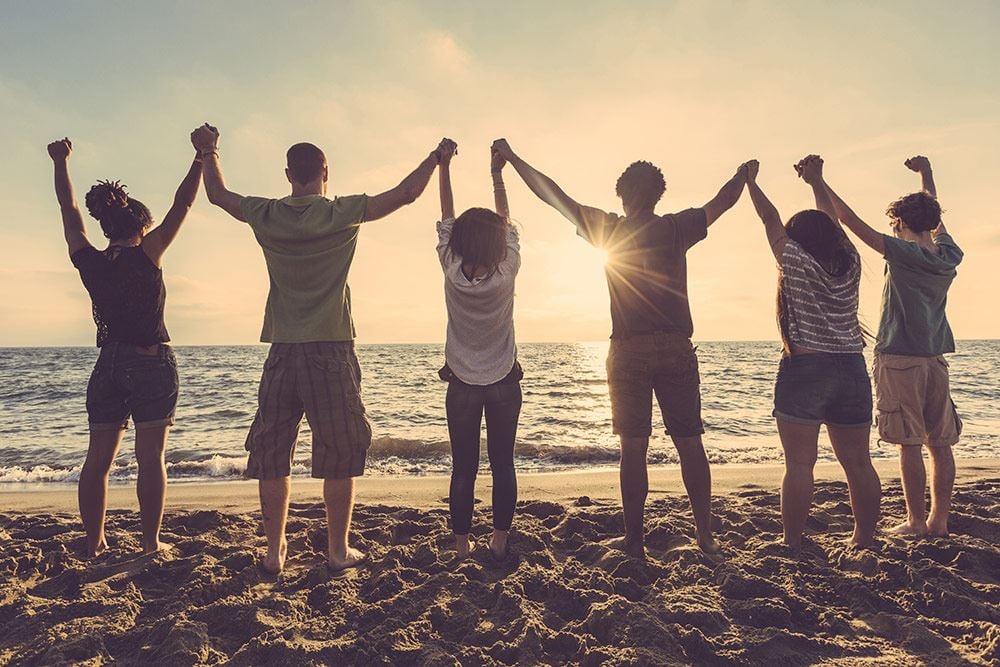 People on beach with arms up  in the air