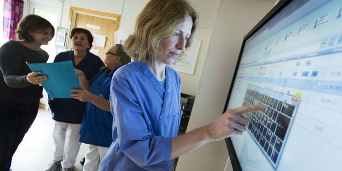 Sykepleier Camilla Baarsrud på Dønskei Trygghetsavdeling legger inn informasjon på den nye touchskjermen. Foto: SINTEF/Werner Juvik.