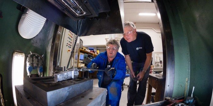 De ønsker å bidra til energibesparende framstilling av aluminium-deler til biler. Verksmester Arne Gellein i SINTEF legger det støpte emnet på plass i smiverktøyet sammen med seniorforsker Martin Lefstad. Foto: SINTEF / Thor Nielsen