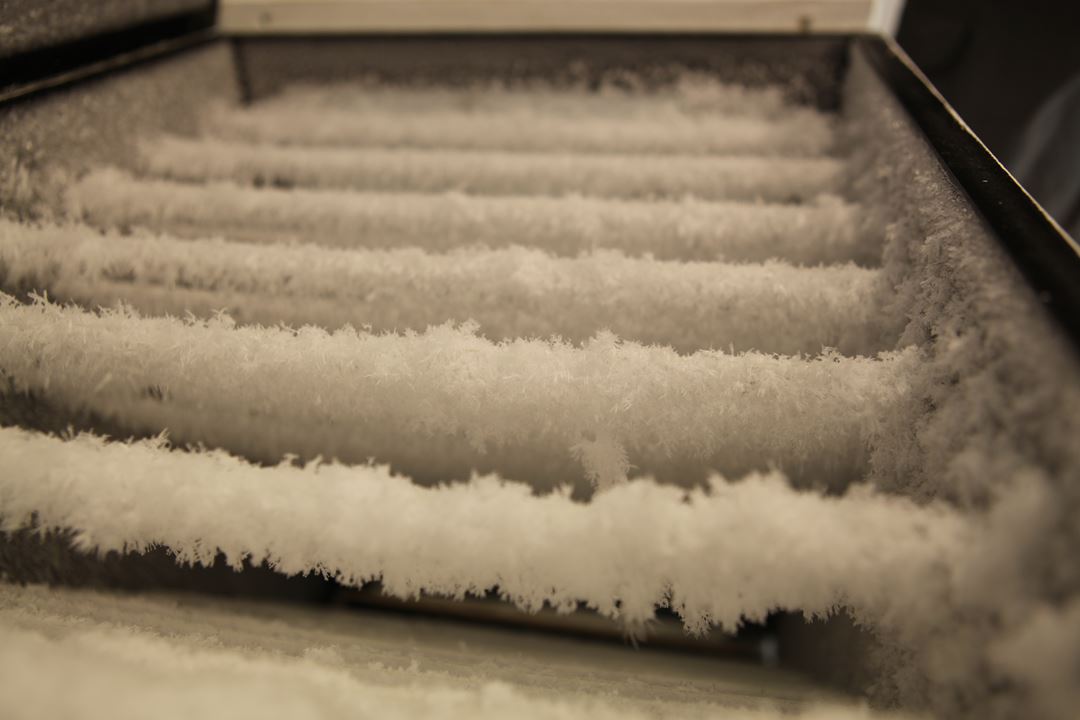 I snømaskinen vokser snøfnugg på fisketråd til dem blir store nok og faller ned når trådene ristes.Foto: NTNU.