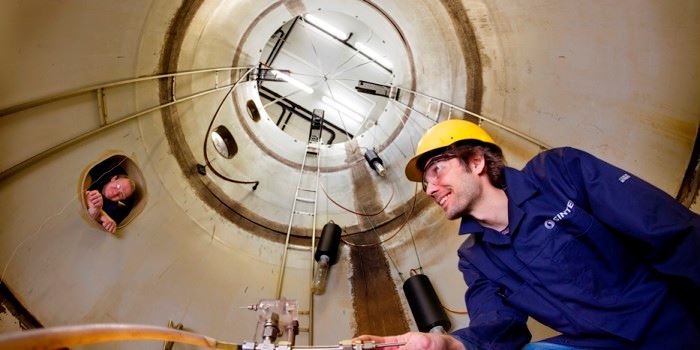 Forsker Jørgen Skancke i bunnen av tårnbassenget. Dysen brukes til å simulere ukontrollerte olje-utslipp, men da er altså den seks meter høye tanken fylt med vann. Ingeniør Frode Leirvik følger med fra et av bassengets vinduer. Foto: Thor Nielsen