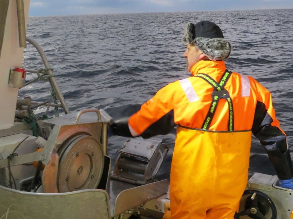 Bilde av fisker i gult oljehyre på linebåt.