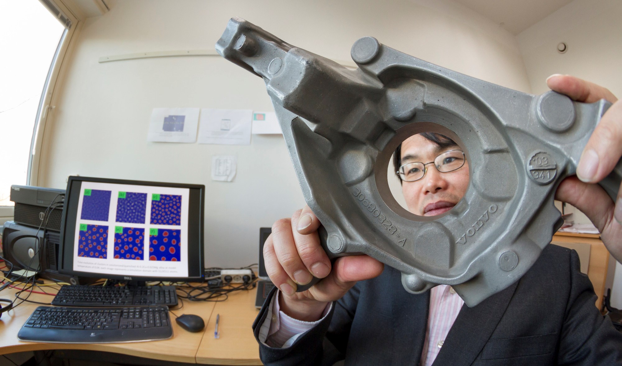 SINTEF-forsker Qiang Du studerer deler av et hjuloppheng som er lagd i aluminium. På skjermen bak seg kan han se inn i bildeler av lettmetall – før de blir produsert. Foto: Thor Nielsen / SINTEF /