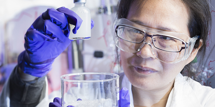 Forsker Juan Yang håper gel-klumpen i flasken vil bidra til økt oljeutvinning. Skåla til høyre rommer ett av råstoffene: milliarder av ørsmå partikler, her oppkonsentrert fra væsken de er født i. Foto: Werner Juvik / SINTEF