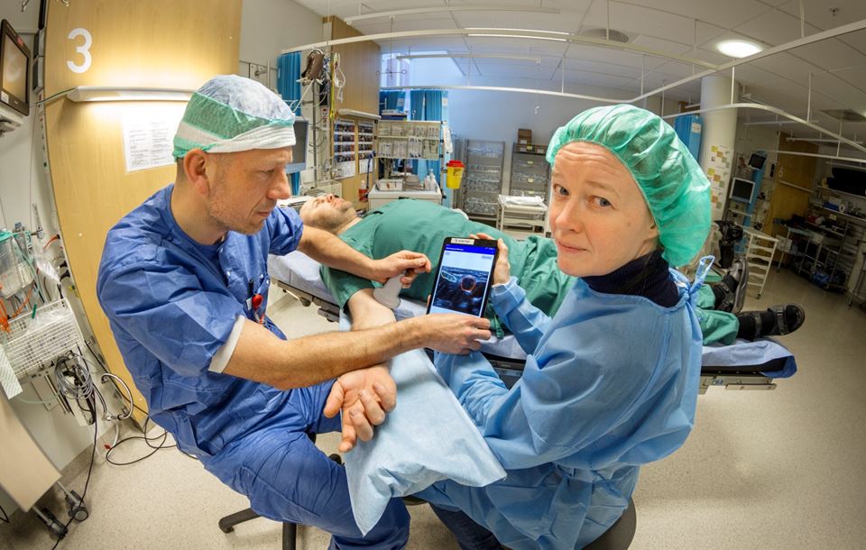 Anestesilege Kaj Fredrik Johansen ved St. Olavs hospital og SINTEF-forsker Ingerid Reinertsen  demonstrerer her et nytt produkt som gir kirurgen ultralydbilder via en app på telefonen. Foto: Thor Nielsen/SINTEF.