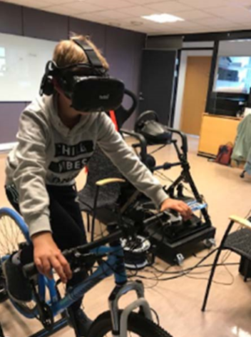 Gutt sykler i sykkelsimulator iført VR-briller.