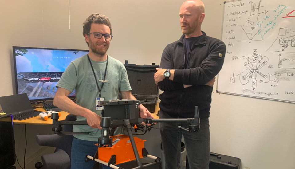 Forskerne Bastien Dupuy (t.v.) og Aslak Einbu viser fram en drone utstyrt med kameraer, bildene brukes til å lage 3D-modeller av terrenget.  Foto: SINTEF/Olav Spanne