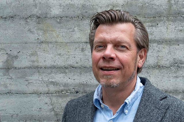 Portrett av mann foran en murvegg