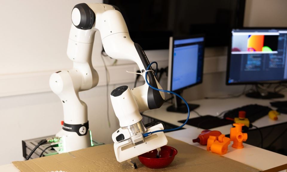Forskerteamet tilfører kunnskap til roboten i simuleringsmiljøet og overfører denne kunnskapen til roboten i den virkelige verden for å få til å gripe nye og ukjente objekter av forskjellig geometri og tekstur. Samtidig er roboten «våken» mens man utfører oppgaven, noe som bidrar til større gripenøyaktighet. Foto: SINTEF