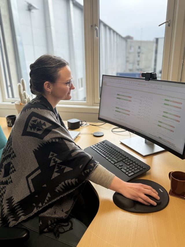 Kvinnelig forsker sitter på kontoret og ser på en analyse på pc-en.
