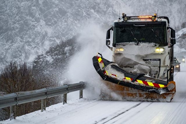 Brøytebil i aksjon på snødekt vei.