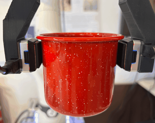 Robotfingre med gripeegenskaper holder en glatt kopp med vann.