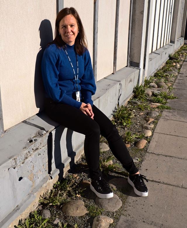 Kvinnelig forsker sitter utenfor bygg med tydelige skader. 