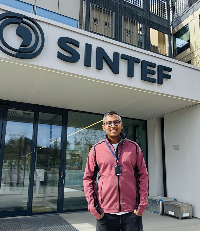 Tekstiler. Rakib Ahmed foran et bygg med SINTEF-logo.