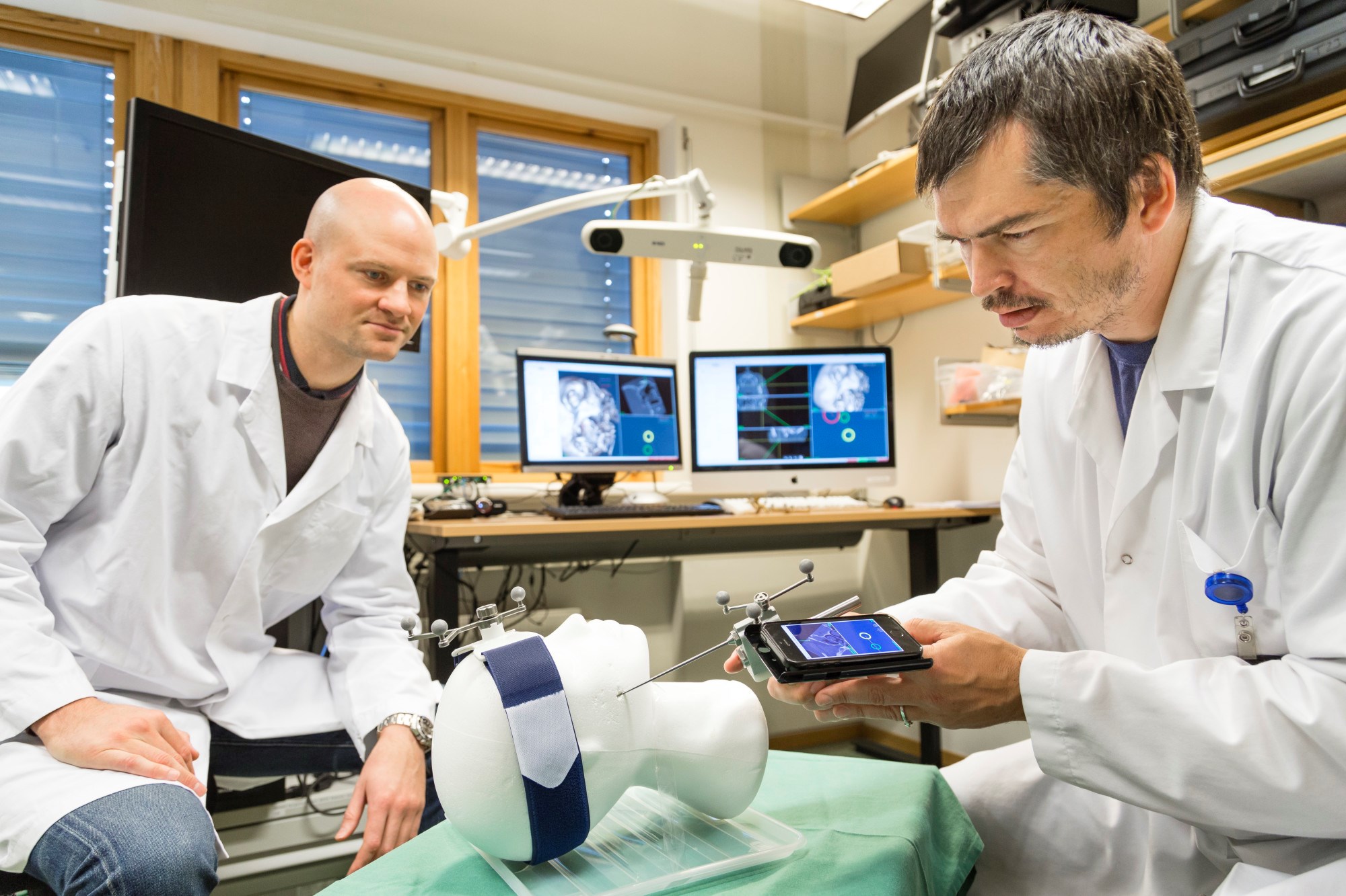 The two SINTEF technologists Christian Askeland (right) and Jon Eiesland seen here testing the new needle guidance system in the laboratory. Photo: Thor Nielsen/SINTEF.