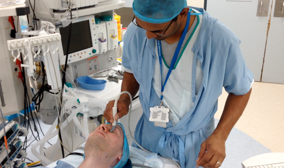 The South African neurosurgeon Llewellyn Padayachy places an ultrasound probe against the eyelid of the patient to measure intracranial pressures. Photo: SINTEF.