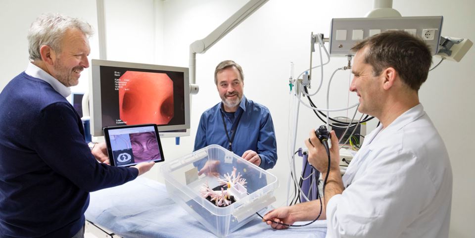 Lung specialist Håkon O. Leira inserts a present-day bronchoscope into a physical model of human lungs. The large screen shows what the examination instrument “sees”. Together, technologists Tor Helge Hansen (left) and Thomas Langø aim to ensure that lung specialists will in the future be able to guide the instrument according to three-dimensional “maps”, using a tablet computer. Photo:  Thor Nielsen / SINTEF